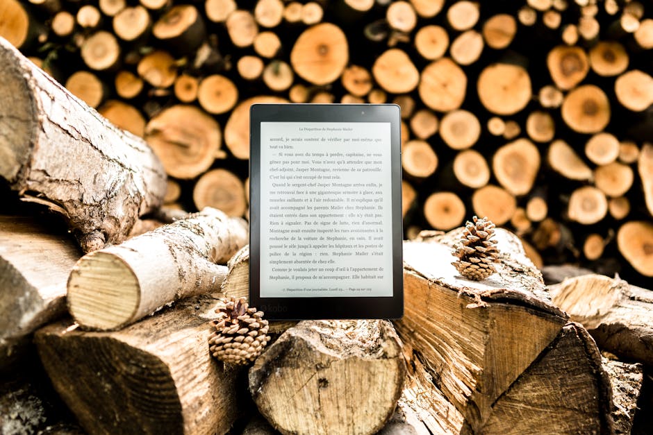 Черная читалка электронных книг на бревнах коричневого дерева