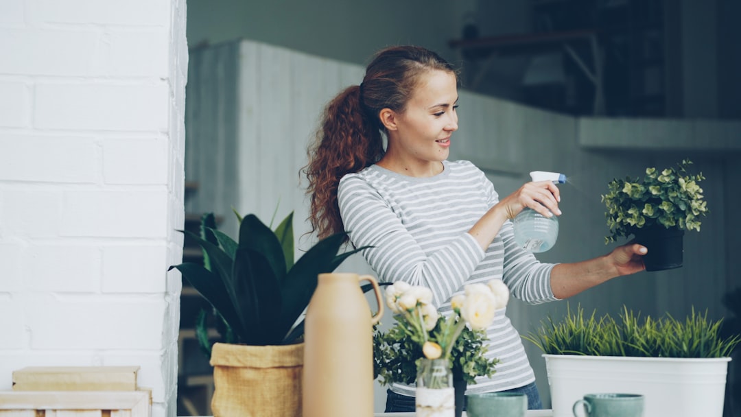 Woman sprays water on a potted plant.